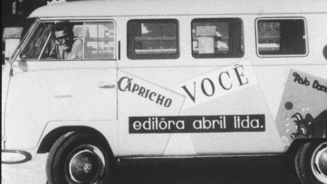 Roberto Civita dirigindo uma Kombi com logotipos de revistas da Editora Abril, no final da década de 50.
