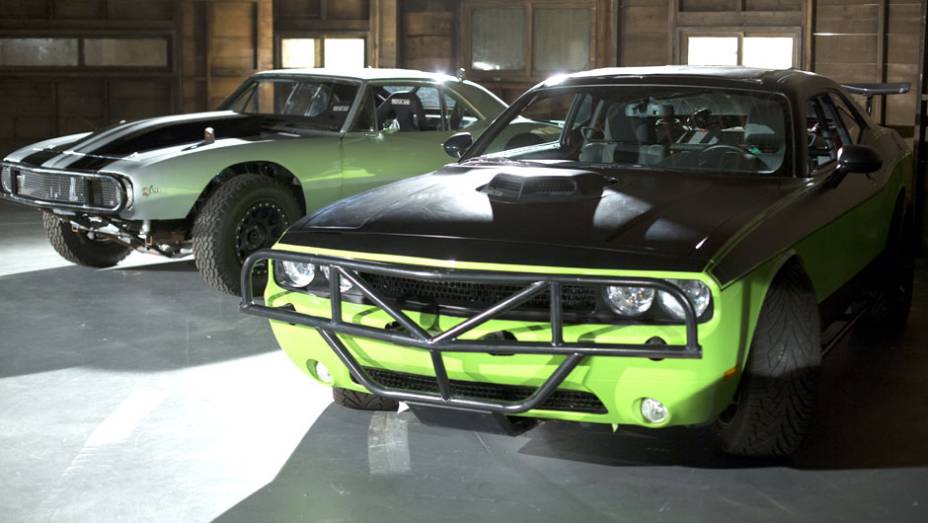 Além do Cuda, Letty também pilota um Dodge Challenger verde bastante modificado; ao fundo, o Chevrolet Camaro de Roman Pearce (Tyrese Gibson) | <a href="https://quatrorodas.abril.com.br/galerias/especiais/gatas-velozes-furiosos-852096.shtml" target="_blank" rel="migration">7</a>