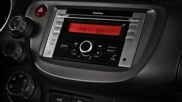 Rádio da versão LX está integrado ao console e vem com entrada USB | <a href="https://quatrorodas.abril.com.br/carros/lancamentos/honda-fit-2013-680204.shtml" rel="migration">Leia mais</a>