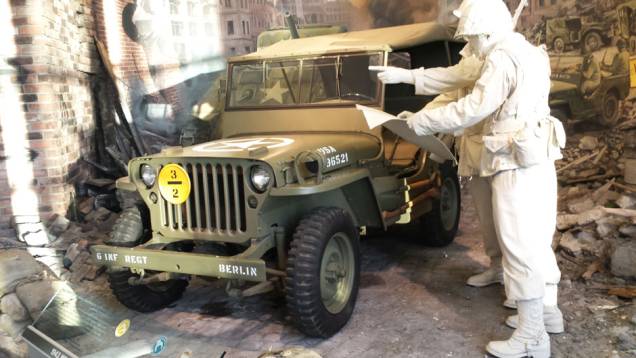 O lendário Jeep Willys aparece em trajes de guerra no meio de um ambiente que reproduz ruínas de uma construção