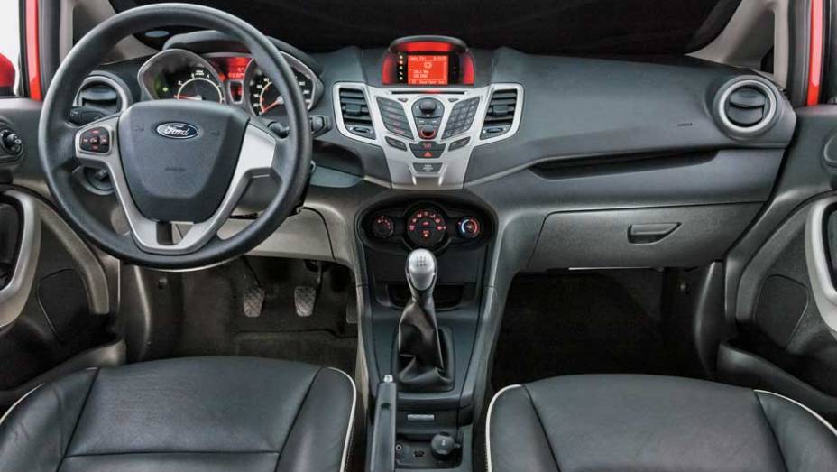 Formato dos botões centrais não favorece a ergonomia | <a href="https://quatrorodas.abril.com.br/carros/comparativos/ford-new-fiesta-x-chevrolet-sonic-699387.shtml" rel="migration">Leia mais</a>