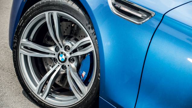 Roda de aro 20 exibe disco de freio ventilado e perfurado | <a href="https://quatrorodas.abril.com.br/carros/comparativos/bmw-m5-x-mercedes-benz-63-amg-737606.shtml" rel="migration">Leia mais</a>