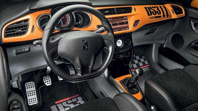 Tapetes, painel e volante seguem a decoração da carroceria, com fibra de carbono, pintura laranja e grafismo militar | <a href="https://quatrorodas.abril.com.br/carros/testes/citroen-ds3-racing-728659.shtml" rel="migration">Leia mais</a>