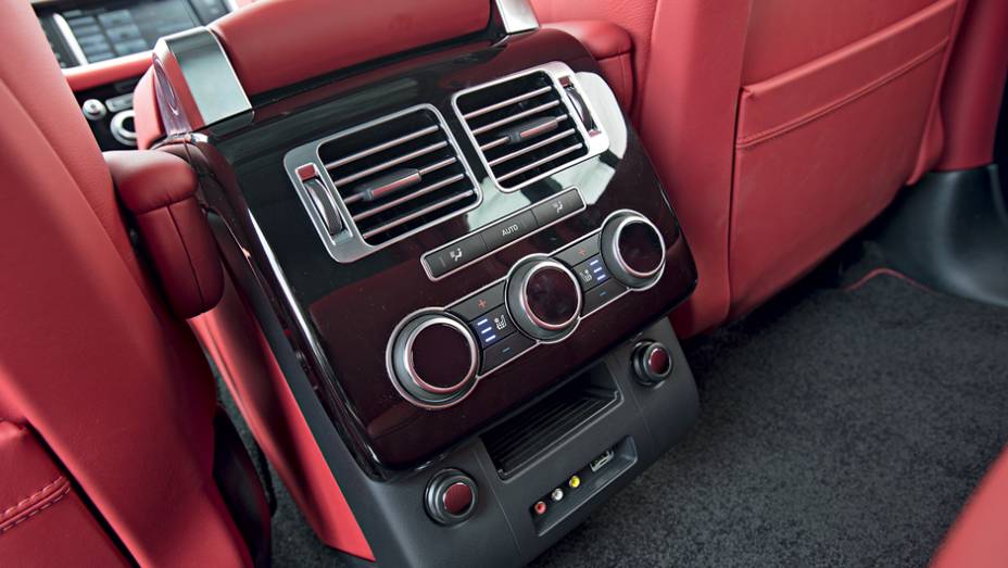 Atrás, um console abriga controles de ventilação e entrada auxiliar | <a href="https://quatrorodas.abril.com.br/carros/testes/land-rover-range-rover-vogue-738240.shtml" rel="migration">Leia mais</a>