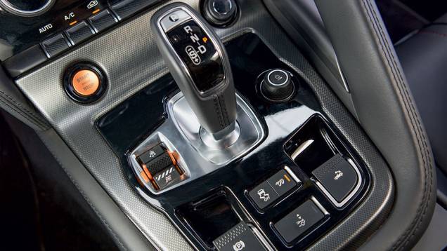 Além do câmbio, o console reúne as teclas do sistema de gestão dinâmica, do freio de estacionamento, do ESP, do sistema sonoro do escapamento, do acionamento do aerofólio e da capota elétrica | <a href="https://quatrorodas.abril.com.br/carros/testes/jaguar" rel="migration"></a> Além do câmbio, o console reúne as teclas do sistema de gestão dinâmica, do freio de estacionamento, do ESP, do sistema sonoro do escapamento, do acionamento do aerofólio e da capota elétrica | <a href="https://quatrorodas.abril.com.br/carros/testes/jaguar" rel="migration"></a>