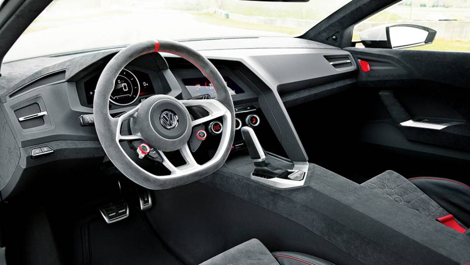 Volante com ponto de referência vermelho no alto e base chata, como num carro de corrida | <a href="https://quatrorodas.abril.com.br/carros/impressoes/volkswagen-design-vision-gti-772455.shtml" rel="migration">Leia mais</a>