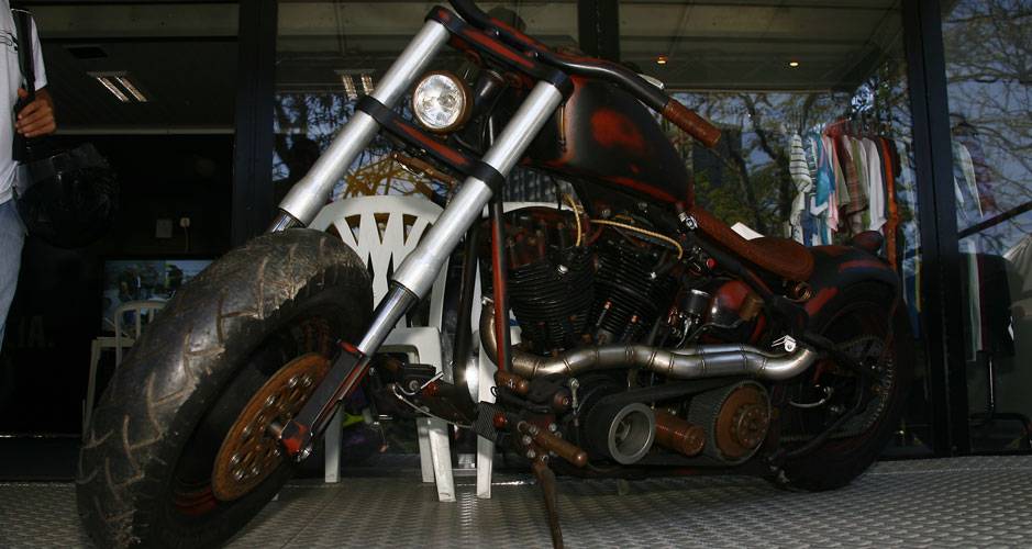 Moto ao estilo Rat Bike surgida a partir dos personagens do filme Mad Max, com motor HD antigo e frente com suspens&atilde;o invertida adaptada | <a href="https://quatrorodas.abril.com.br/moto/noticias/two-wheels-brazil-reune-fabricantes-nacionais-americanos-motos" rel="migration"></a>