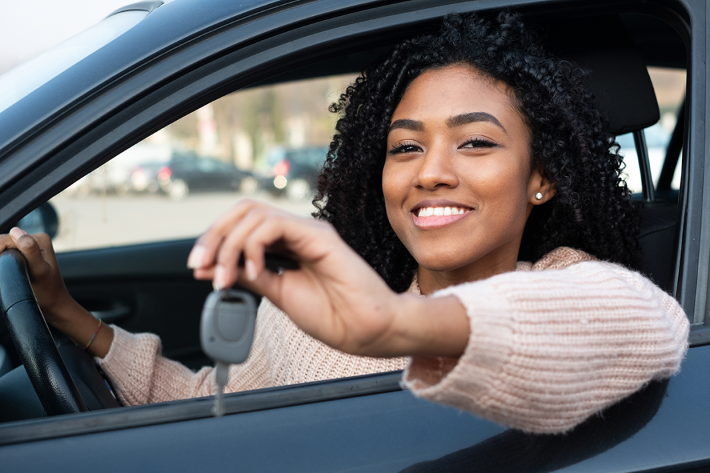 Mulher Preta Sorrindo Segurando chave de carro dentro do veículo. Karvi, plataforma online para vendas de carro.