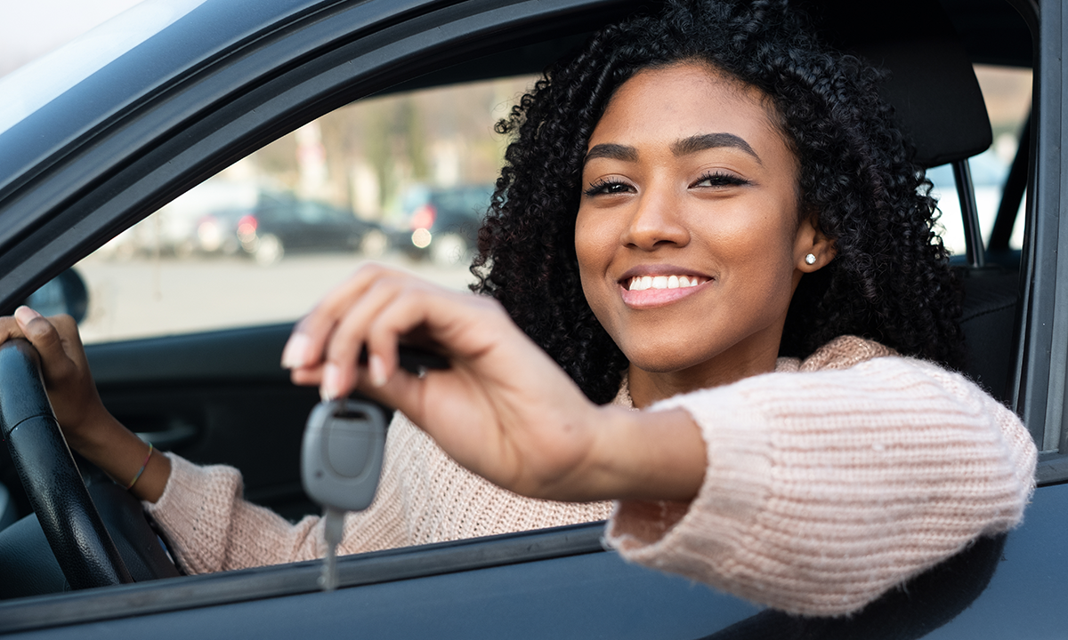 Mulher Preta Sorrindo Segurando chave de carro dentro do veículo. Karvi, plataforma online para vendas de carro.