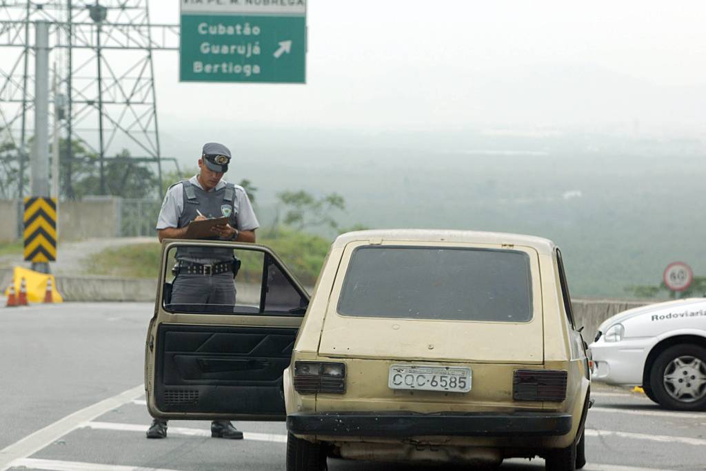 Vagner Beltran, soldado da Polícia Rodoviária autuando o Fiat 147, em péssimo estado de conservação e com documentação irregular, dirigido por Sérgio Ruiz Luz, editor da revista Quatro Rodas, para elaboração de matéria demonstrando o quanto a fiscalização é ineficaz.