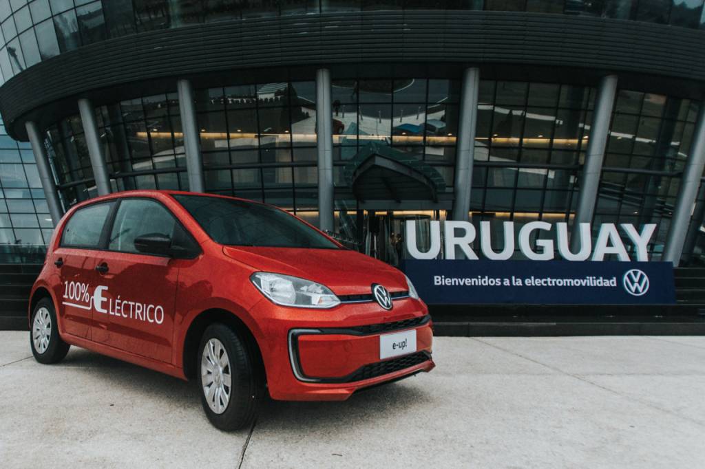 VW e-UP elétrico laranja com placa do Uruguai ao fundo