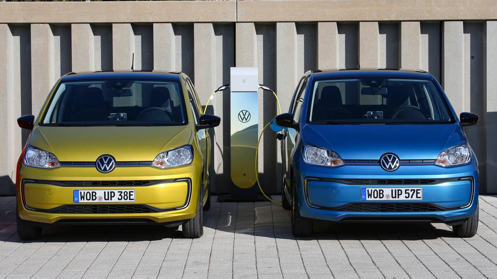 Dois VW e-Up!, um azul e outro amarelo carregando vistos de frente
