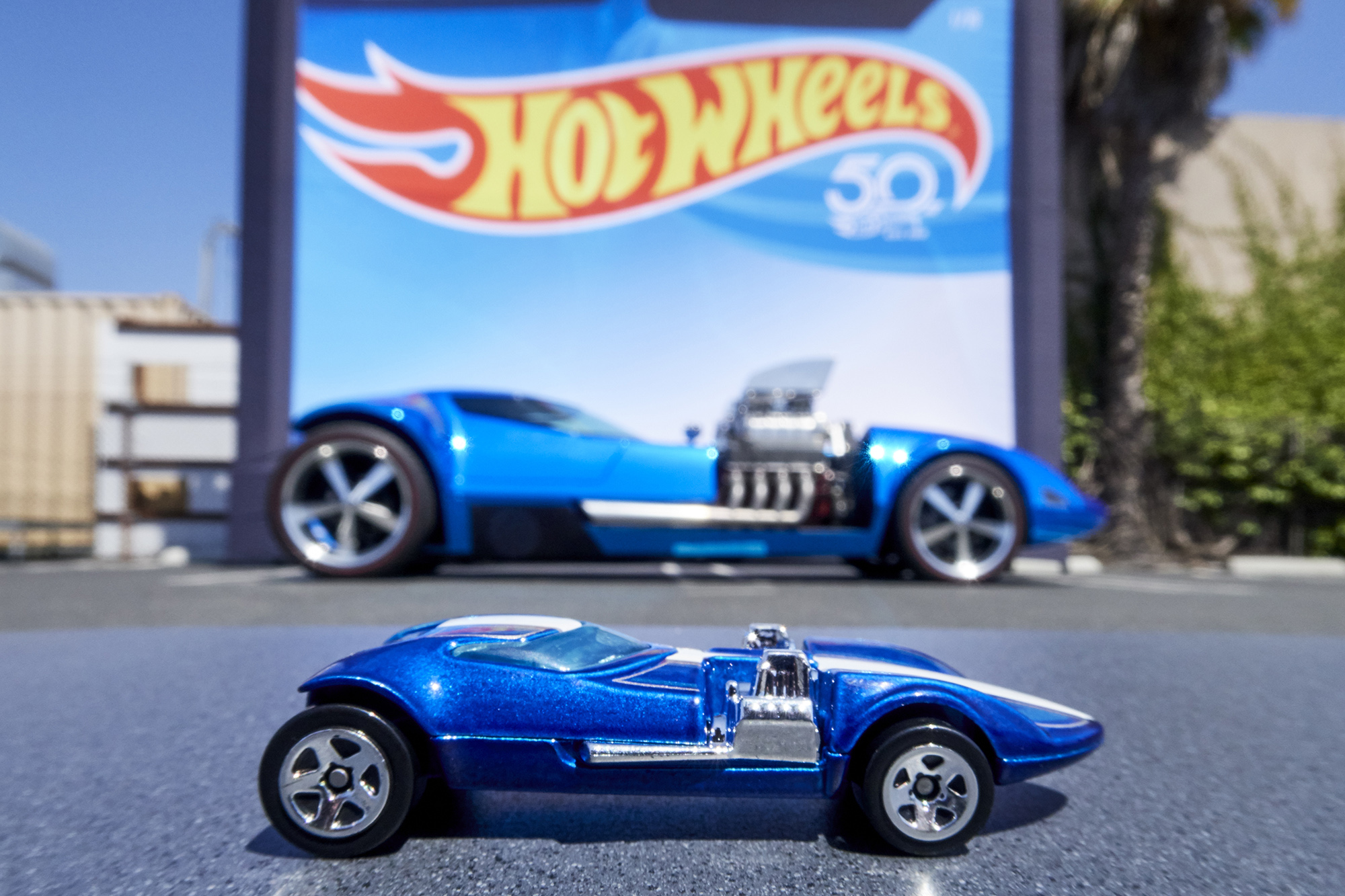 Modelo azul atrás de uma miniatura Hot Wheels azul vista de lado