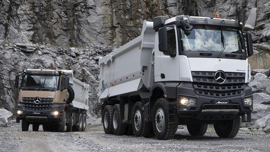 Dois Mercedes-Benz Arocs marrom e branco vistos de frente