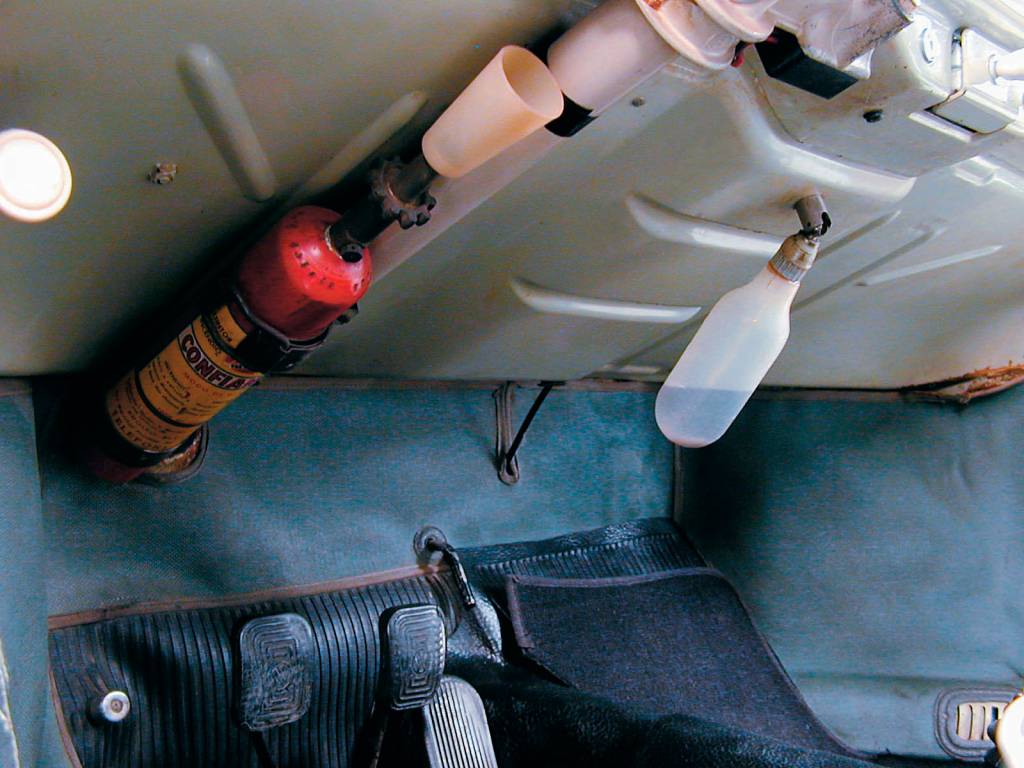 Parte baixa do painel do Fusca, da Volkswagen, modelo 1960, vendo-se o extintor de incêndio e a garrafinha do esguicho do pára-brisa