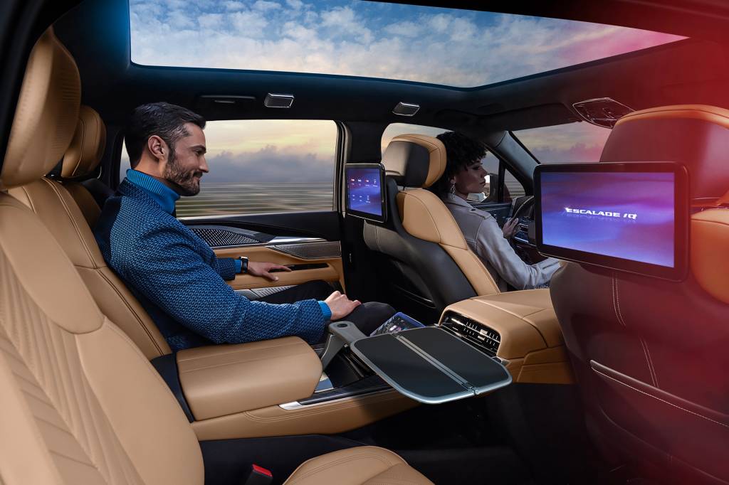 Man sitting in Executive Second Row of Cadillac ESCALADE IQ with backseat screens.