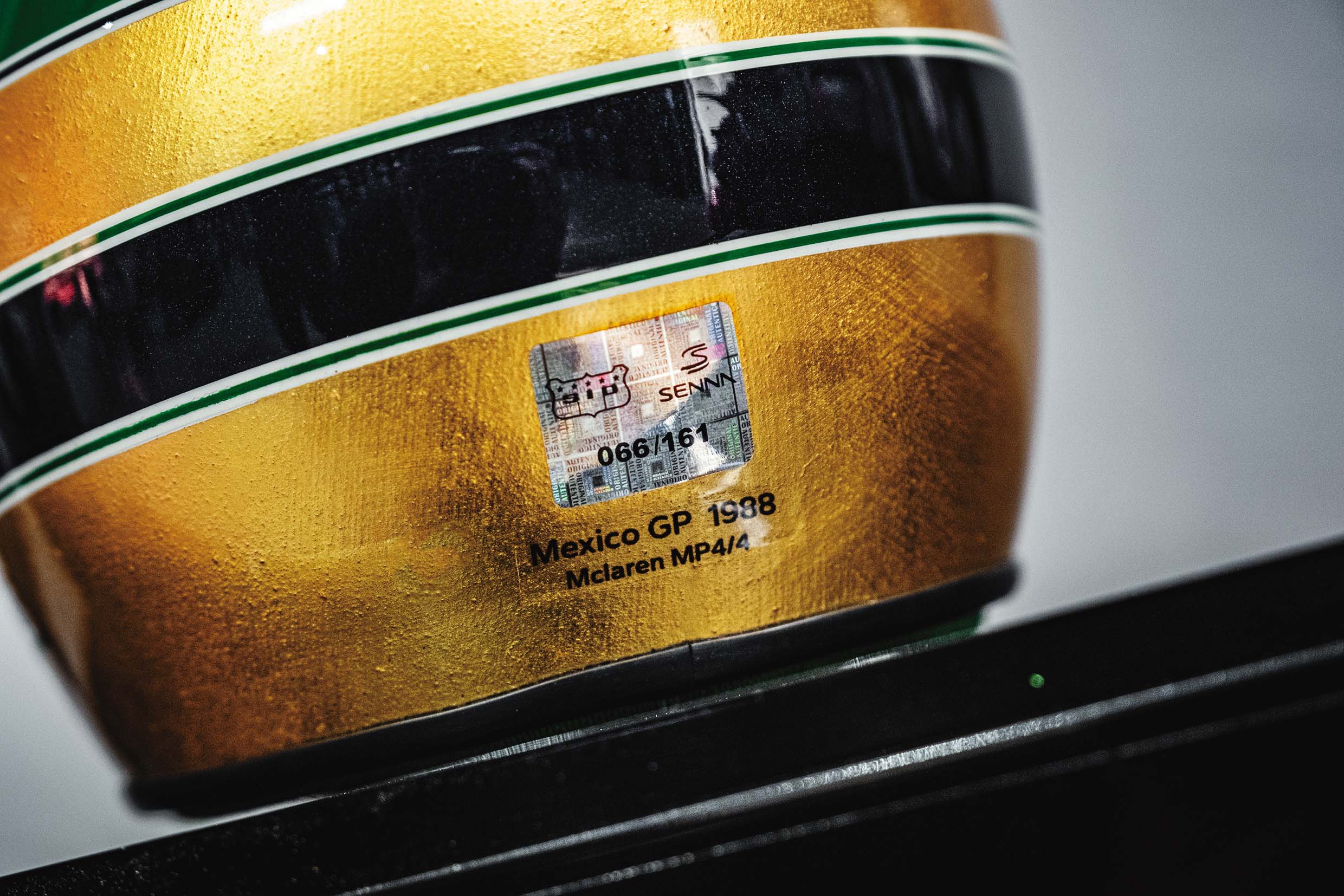 Miniaturas do capacete dourado, numeradas e com informações sobre Grandes Prêmios