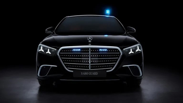 Carro Mercedes-Benz S 680 Guard preto, blindado, com luzes de emergência azuis no teto e na grade frontal, em um fundo escuro