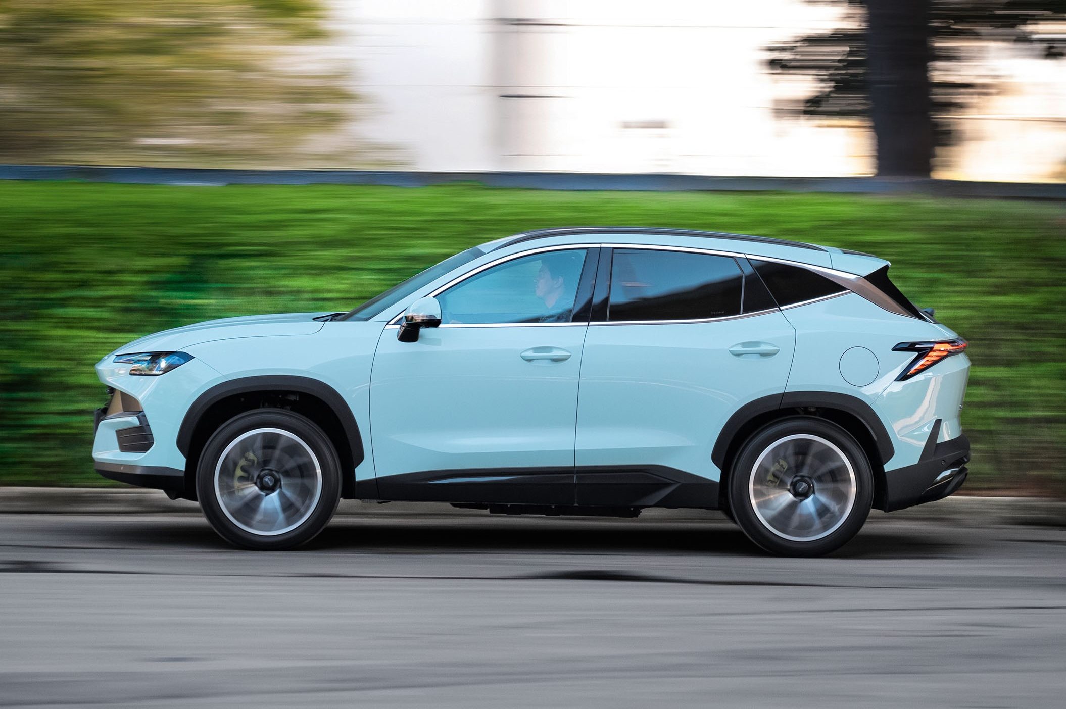SUV azul-claro em movimento, visto de lado, com o fundo borrado por efeito de velocidade. O veículo tem detalhes em preto nas caixas de roda e na parte inferior da carroceria, e rodas de liga leve prateadas.
