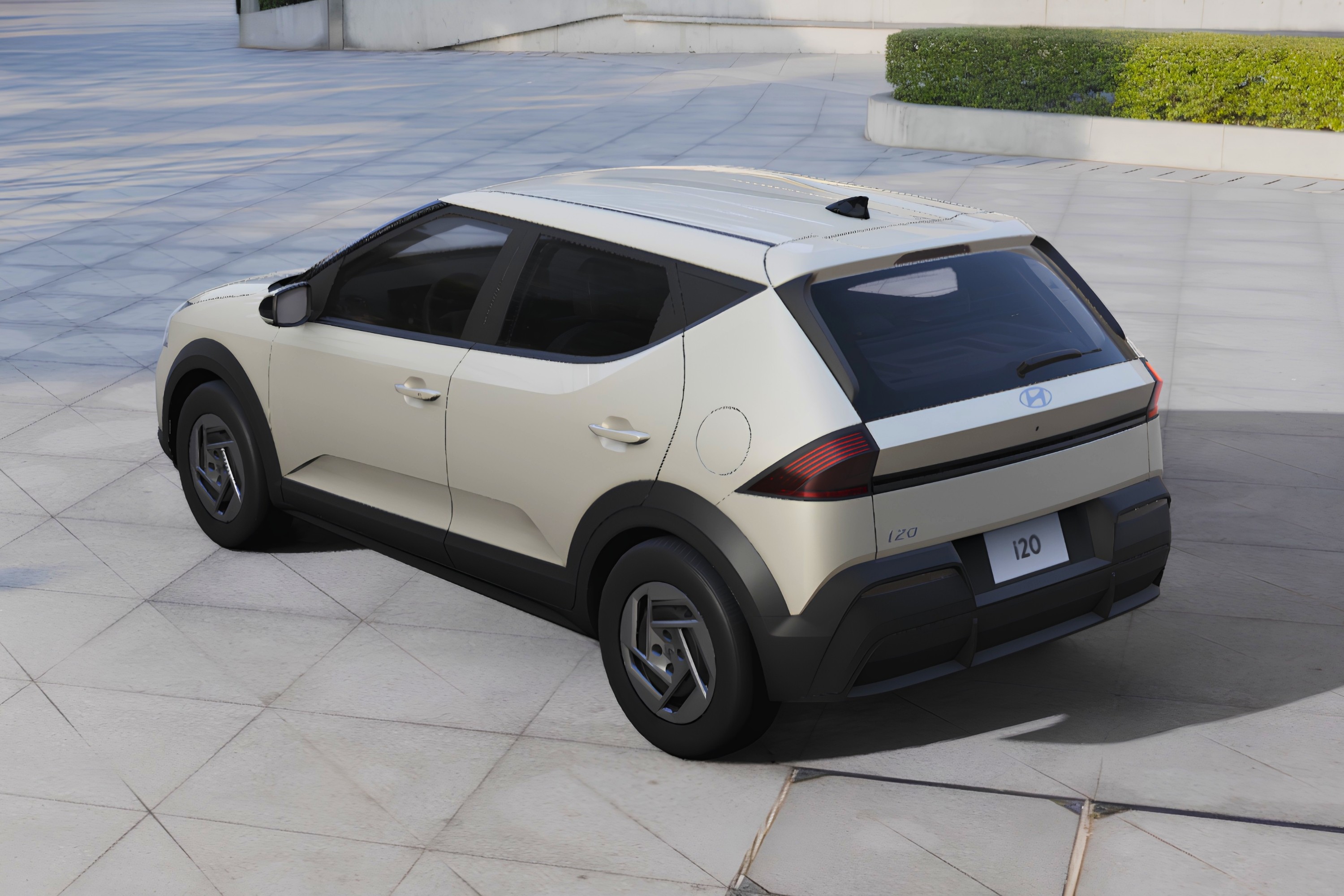 Carro Hyundai i20 bege claro, visto de cima e traseira, estacionado em piso de concreto com blocos quadrados. O veículo tem detalhes em preto fosco nas caixas de roda e para-choque traseiro, e rodas de liga leve cinza escuro. Ao fundo, um canteiro com arbustos verdes e uma construção moderna.