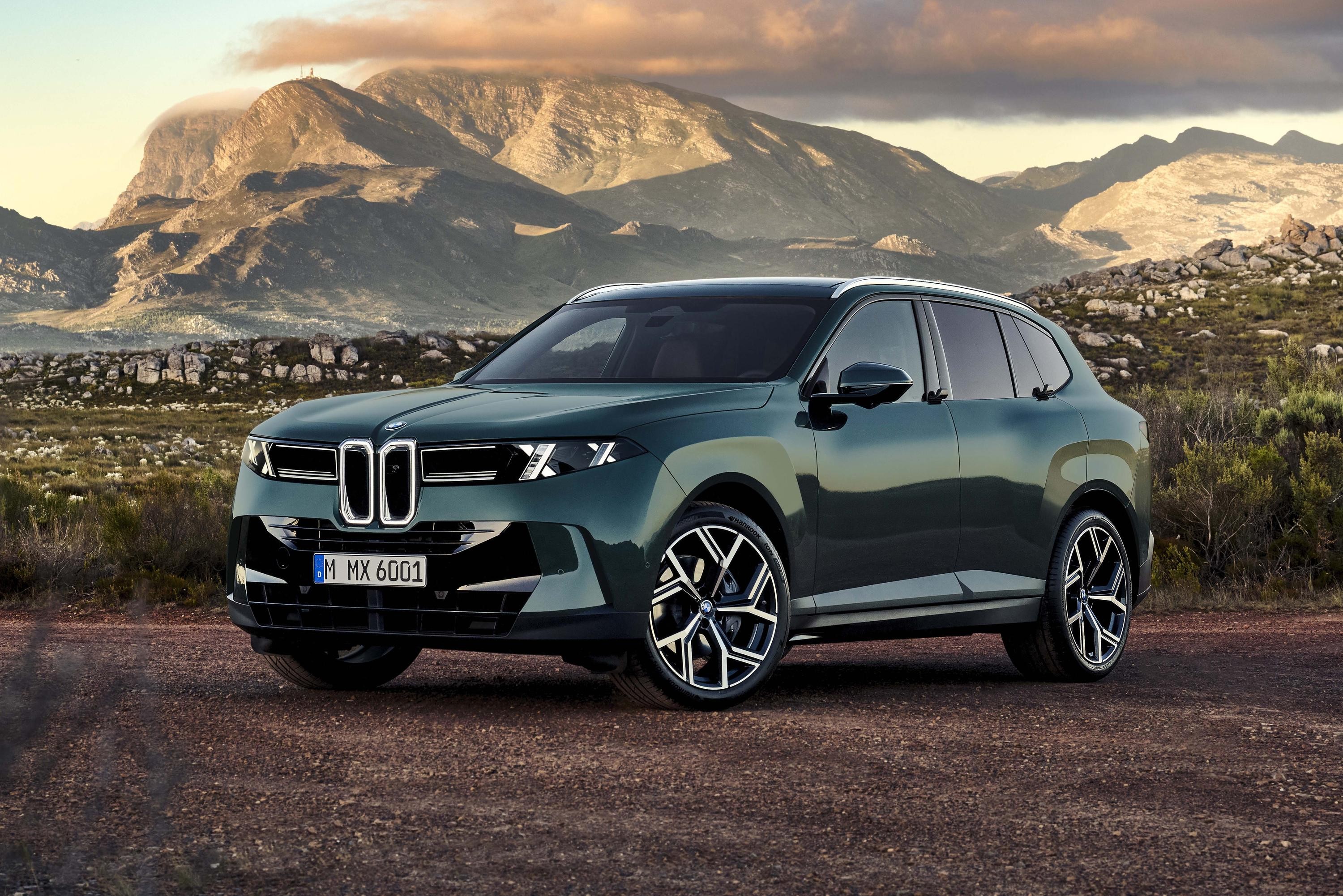 Um SUV verde-escuro com design moderno e faróis afilados, parado em uma estrada de terra. Ao fundo, montanhas rochosas sob um céu com nuvens alaranjadas no pôr do sol