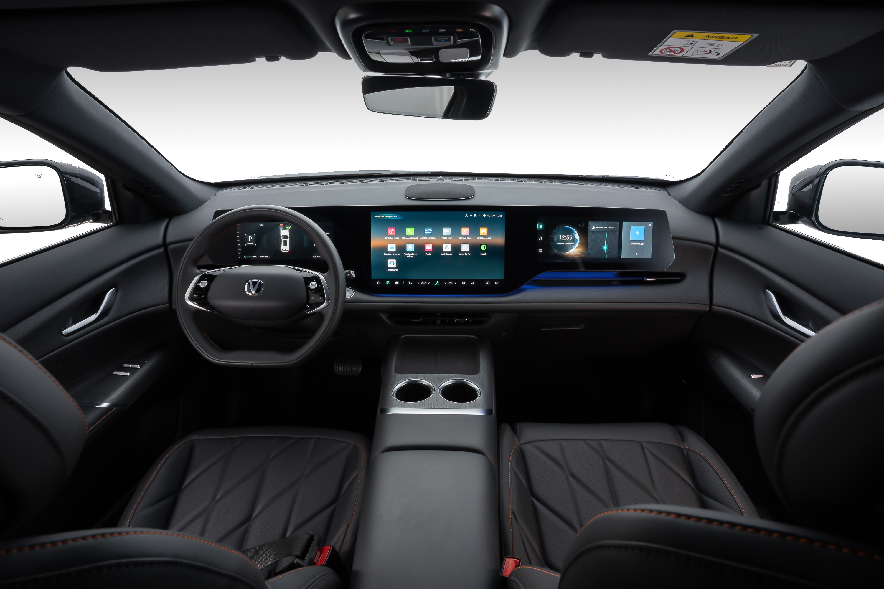 Interior de carro moderno com painel digital amplo, volante multifuncional e bancos de couro pretos com costura laranja. O painel exibe ícones de aplicativos e informações do veículo.