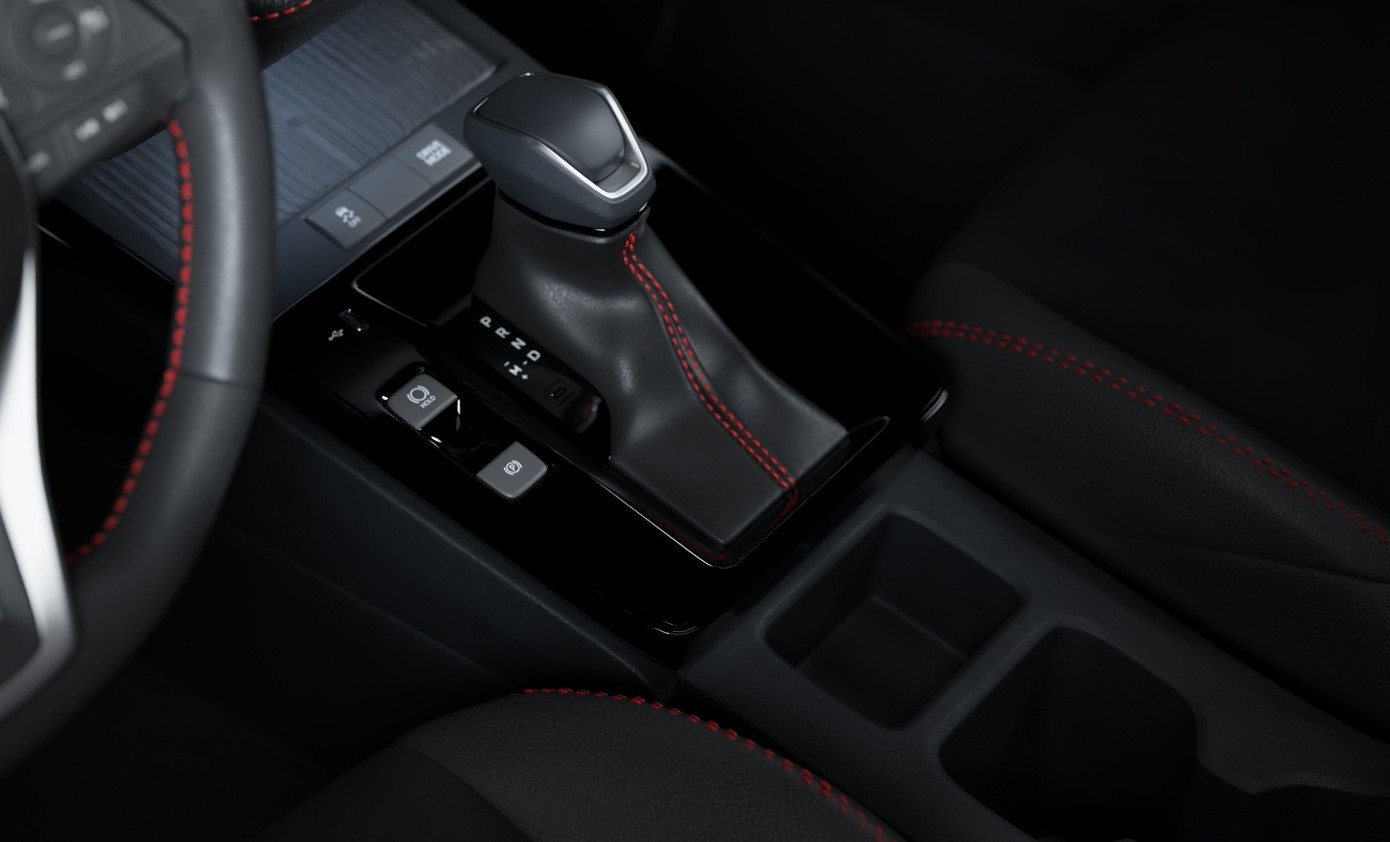 Interior de um carro com câmbio automático preto e costura vermelha, volante parcialmente visível à esquerda com costura vermelha, e assento escuro com costura vermelha à direita. Detalhes do console central incluem botões e porta-copos.