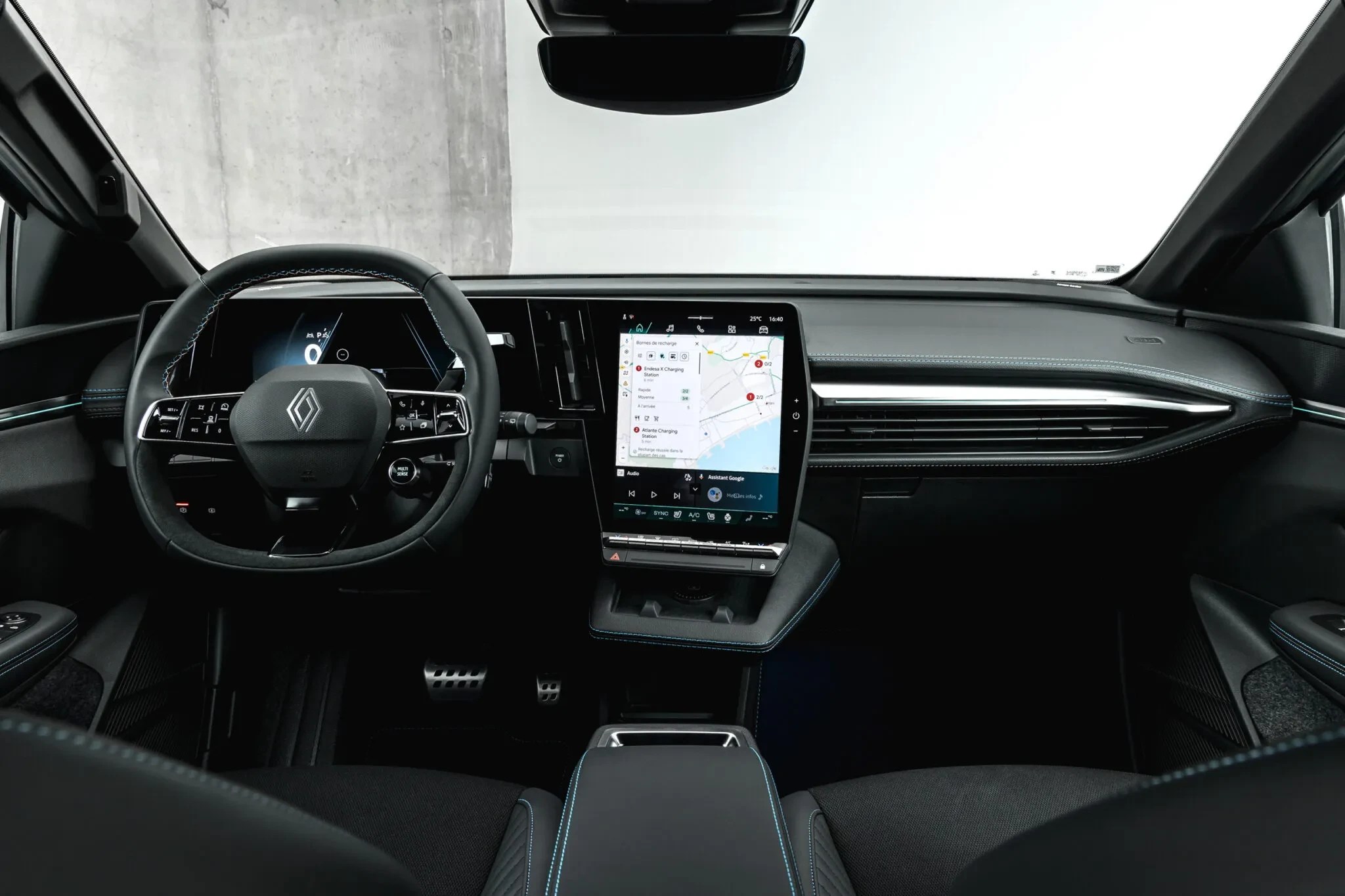 Interior de um carro moderno com volante multifuncional e tela vertical exibindo um mapa de navegação. O painel é preto com detalhes em costura azul e saídas de ar horizontais.