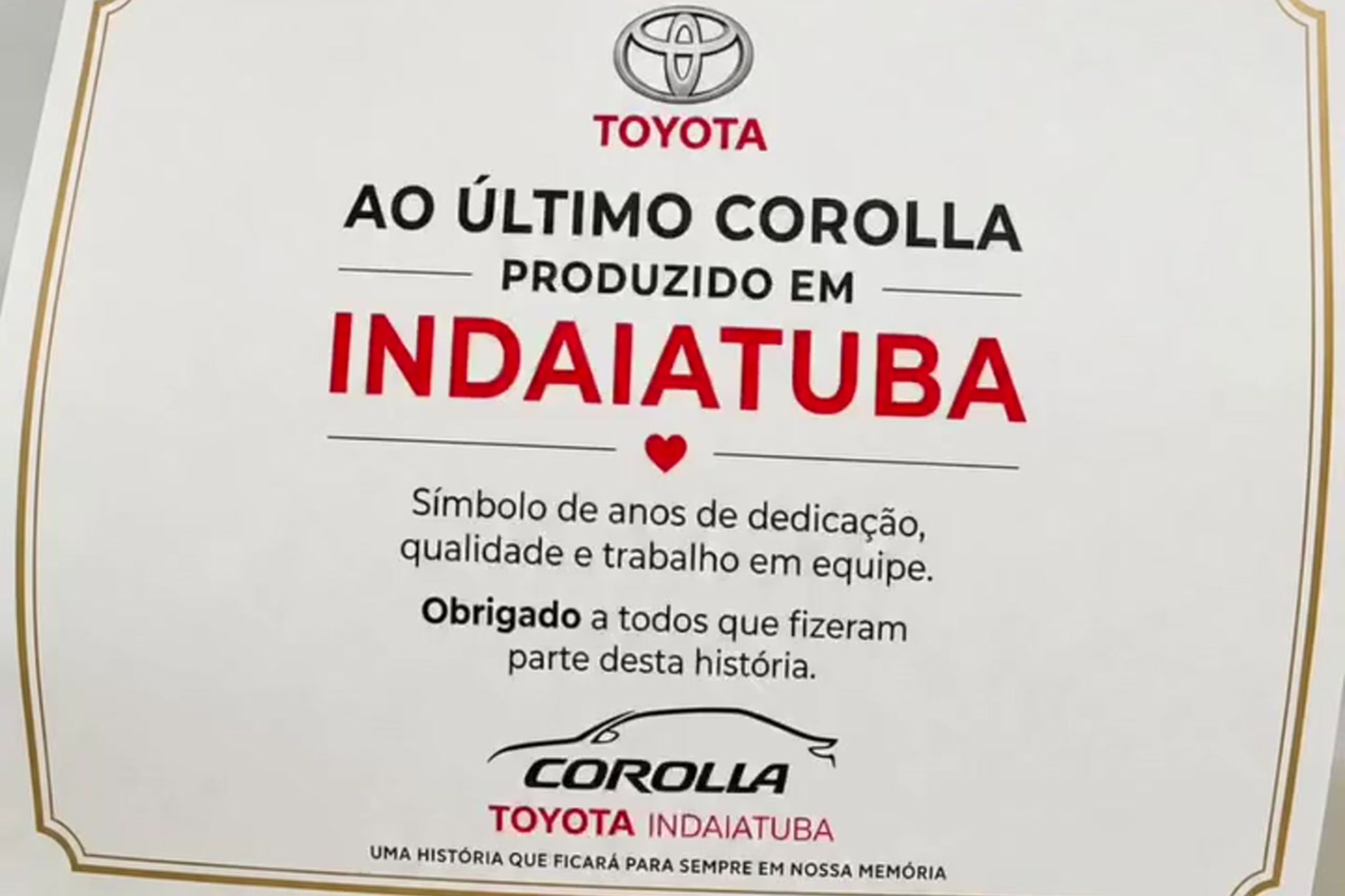 Certificado branco com borda dourada, exibindo o logo Toyota e o texto AO ÚLTIMO COROLLA PRODUZIDO EM INDAIATUBA, com um coração vermelho. Abaixo, Símbolo de anos de dedicação, qualidade e trabalho em equipe. Obrigado a todos que fizeram parte desta história. No final, um desenho do carro Corolla e TOYOTA INDAIATUBA UMA HISTÓRIA QUE FICARÁ PARA SEMPRE EM NOSSA MEMÓRIA
