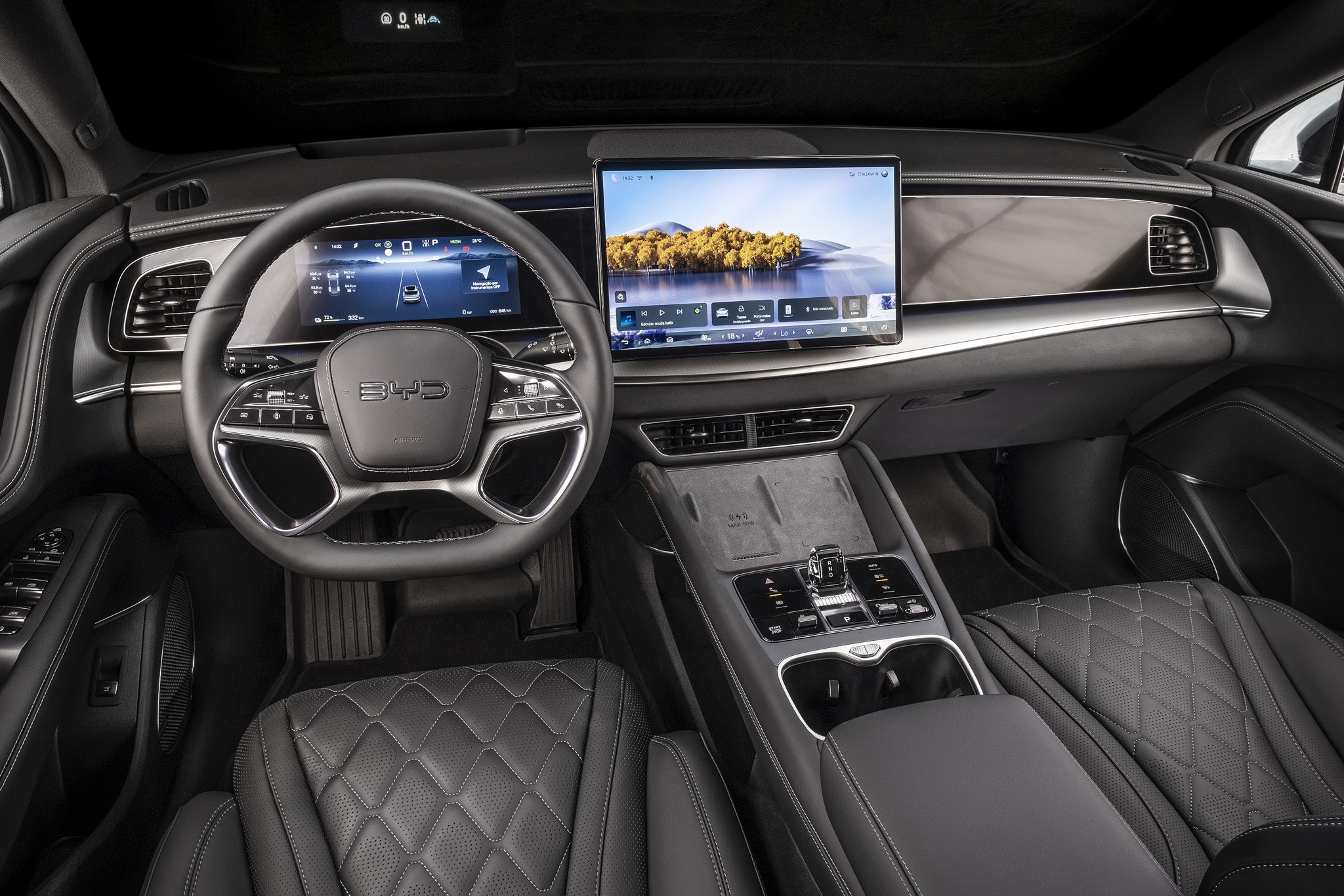 Interior de um carro moderno com volante multifuncional preto e prateado, painel digital exibindo informações de direção e uma grande tela central mostrando uma paisagem com árvores e água. Os bancos de couro preto têm costura em formato de diamante, e o console central possui botões de controle e porta-copos.