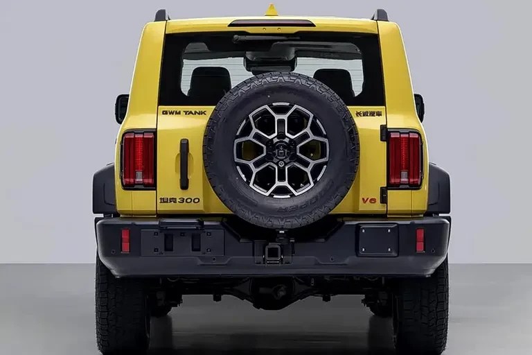 Traseira de um SUV amarelo vibrante, com pneu estepe centralizado na porta do porta-malas. Lanternas verticais vermelhas, para-choque preto robusto, e detalhes como GWM TANK e V6 em relevo. O veículo está estacionado em um piso escuro, com fundo cinza claro