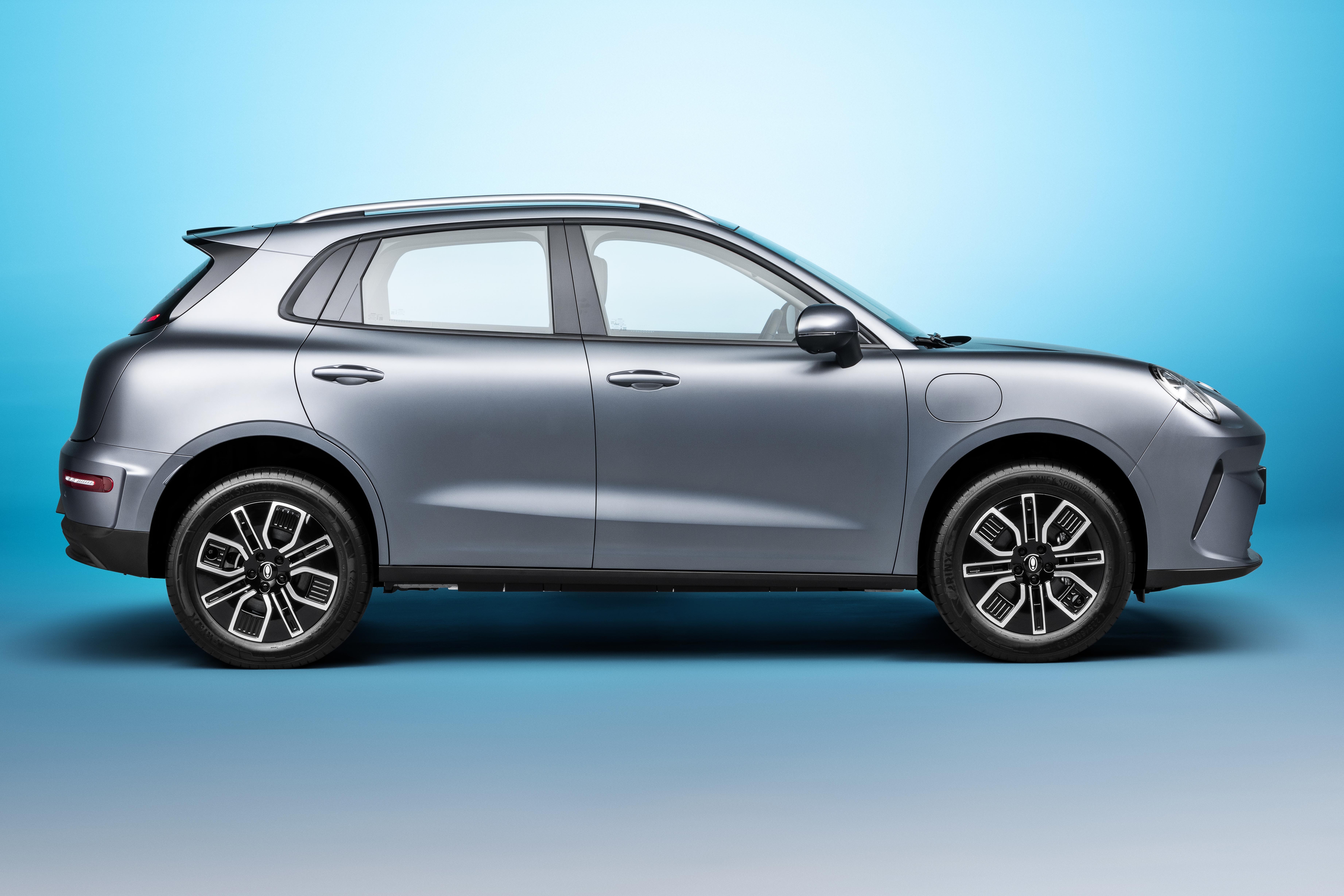 SUV elétrico cinza-chumbo, visto de perfil, com teto solar e rodas pretas com detalhes prateados, em fundo azul degradê