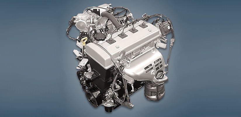 Motor de carro prateado e preto, com várias mangueiras e fios conectados, visto de cima em um fundo azul escuro