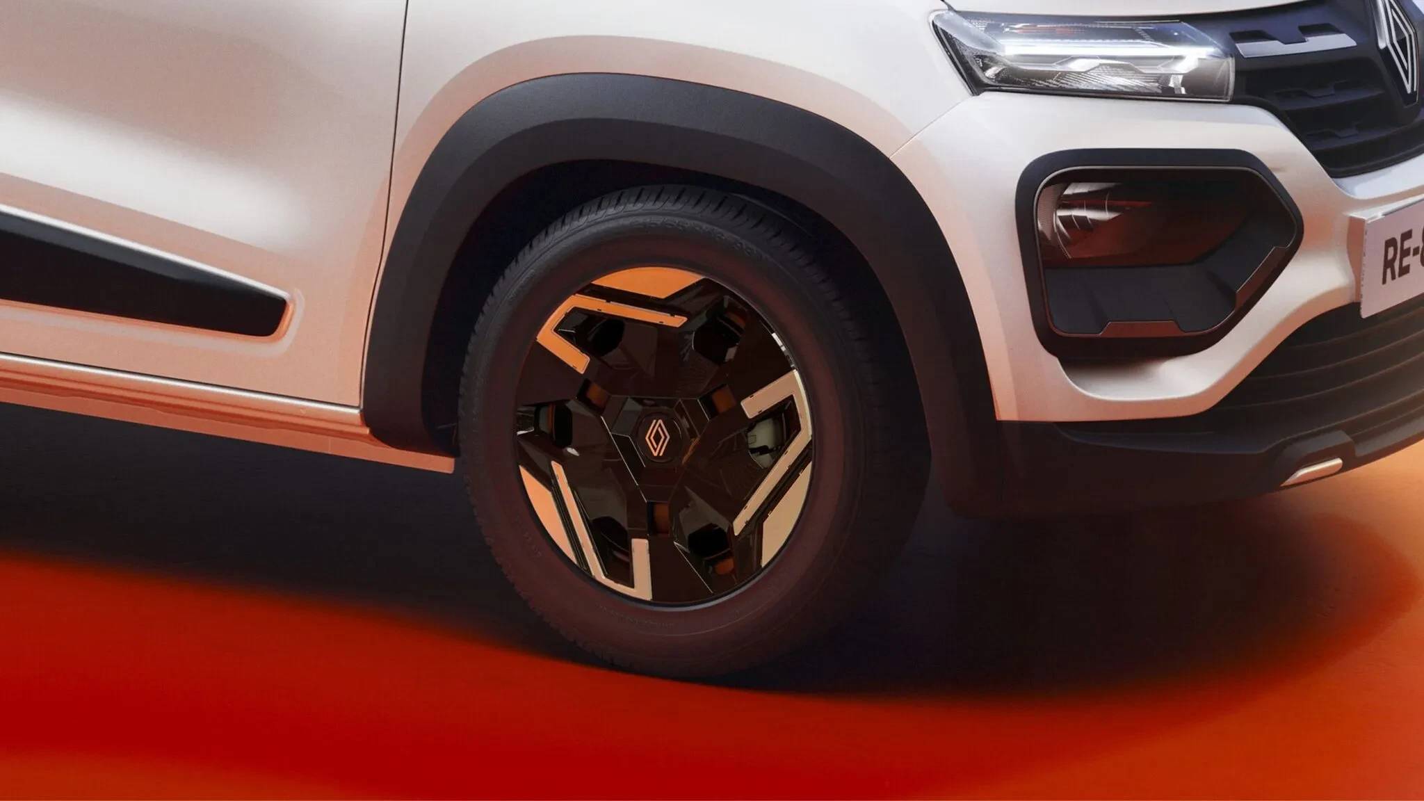 Parte frontal de um carro branco com detalhes em preto, incluindo a roda dianteira com calota preta e detalhes em laranja, para-lama preto e farol aceso. O veículo está sobre um fundo laranja