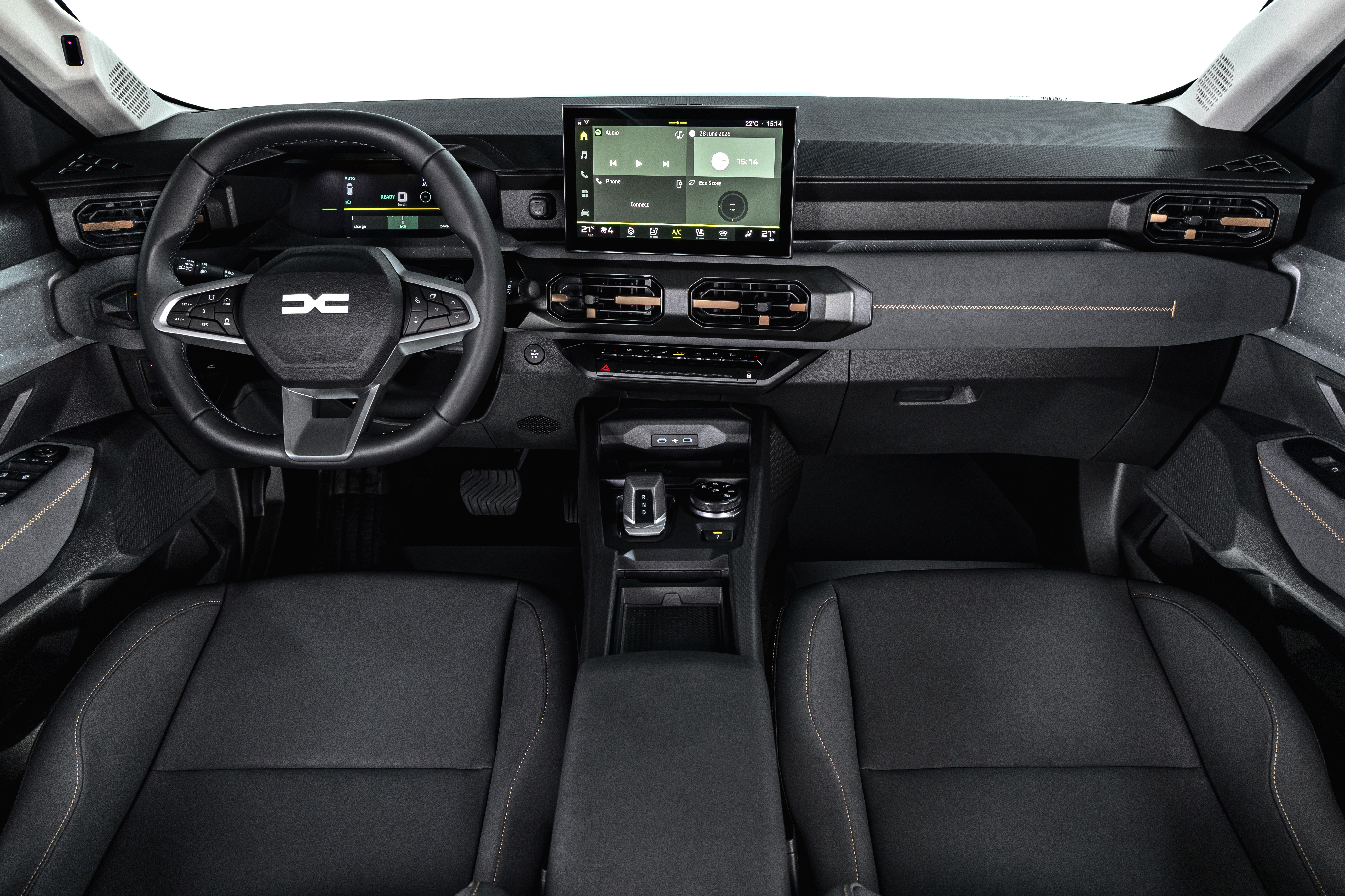 Interior de um carro moderno, com painel escuro e detalhes em bronze. Volante multifuncional com logo Dacia, tela multimídia central exibindo um player de música, saídas de ar retangulares e bancos pretos de couro com costura branca. O console central possui porta-copos e compartimentos