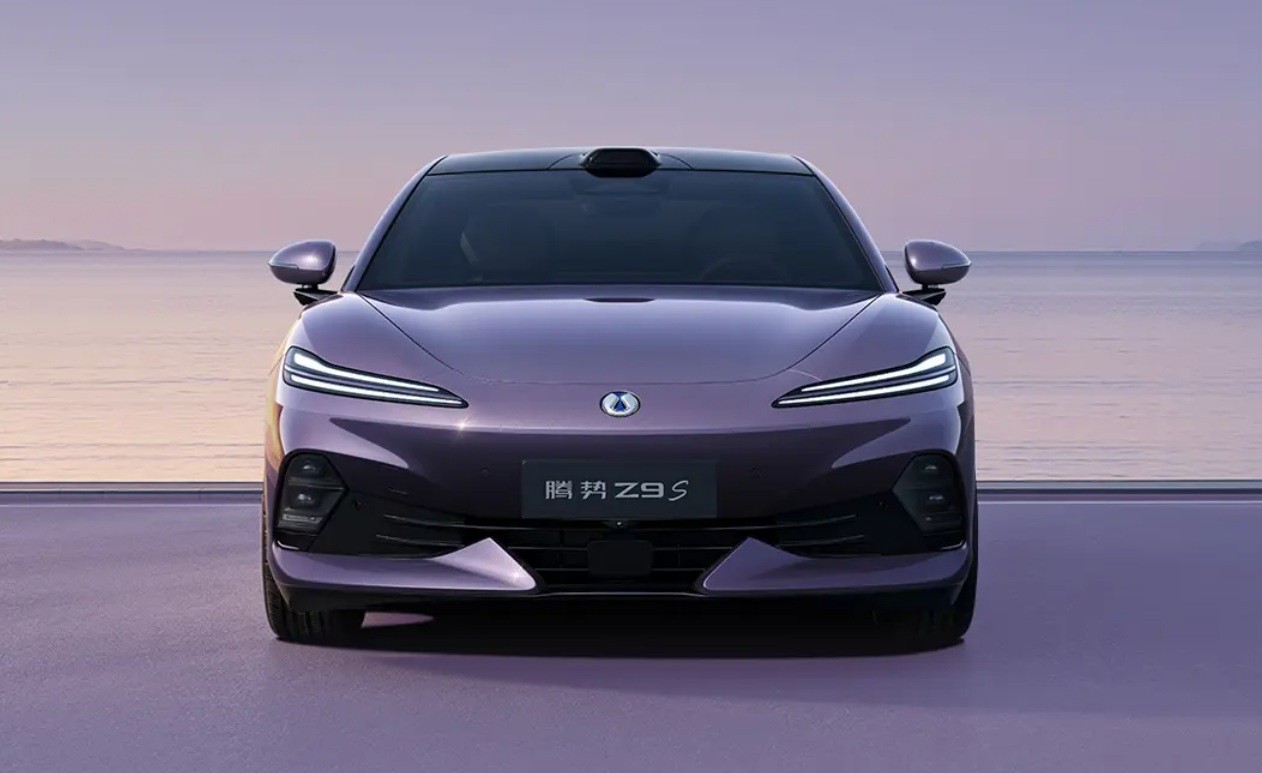 Carro elétrico Denza Z9 GT roxo com faróis em LED acesos, parado em uma estrada à beira-mar ao entardecer