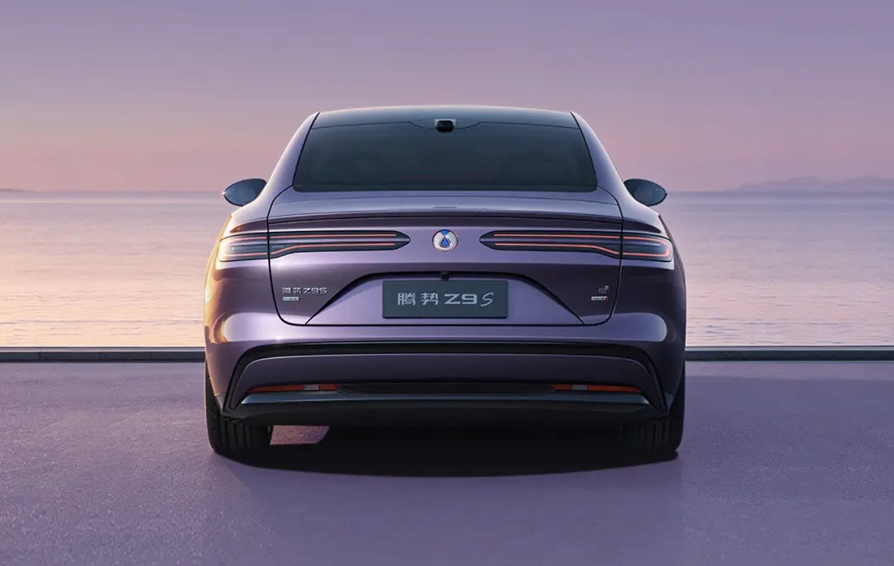 Traseira de um carro roxo escuro, com lanternas horizontais finas e o nome 腾势 Z9 S na placa, estacionado em uma superfície roxa clara. Ao fundo, um oceano calmo sob um céu em tons de roxo e rosa no pôr do sol