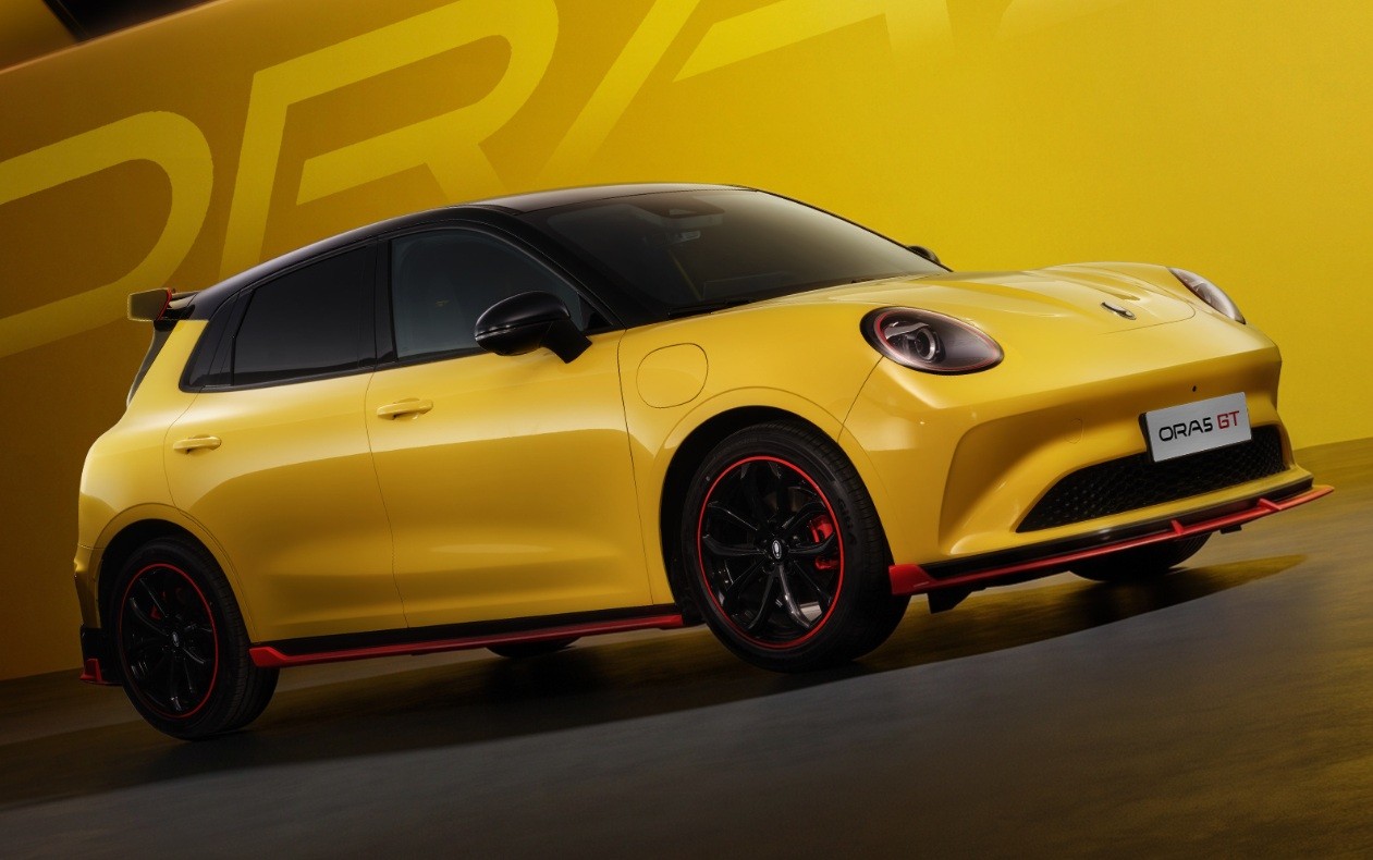 Carro elétrico Ora GT amarelo e preto, com rodas pretas e detalhes vermelhos, em um estúdio com fundo amarelo e o nome ORA em destaque
