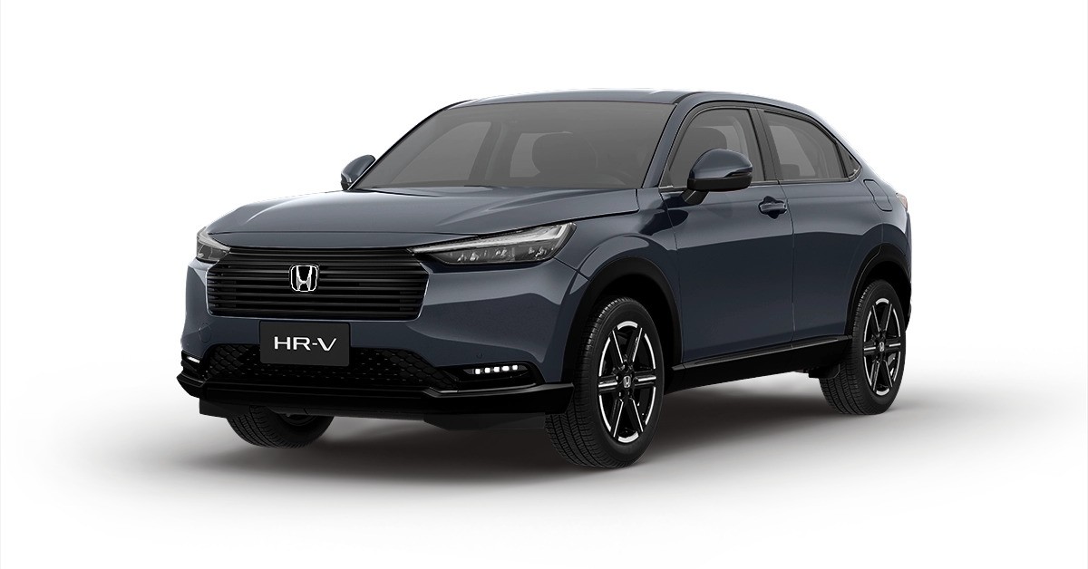 SUV Honda HR-V 2023 cinza escuro, visto de frente e levemente de lado, com faróis acesos e grade frontal preta, sobre fundo branco