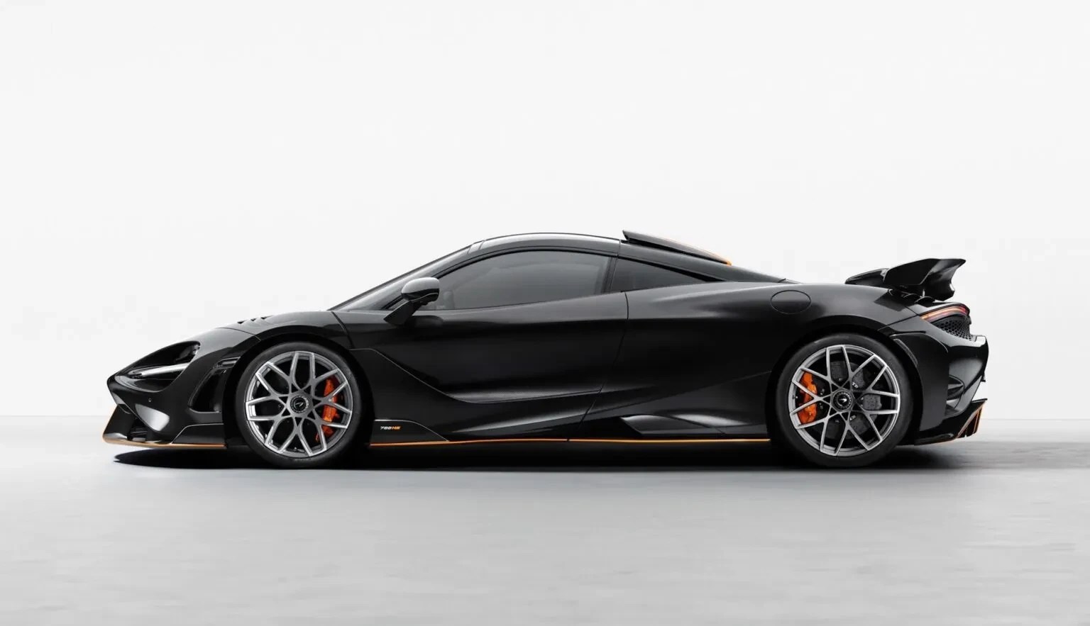 Carro esportivo McLaren 720S preto, visto de perfil, com rodas prateadas e pinças de freio laranja, em um estúdio branco