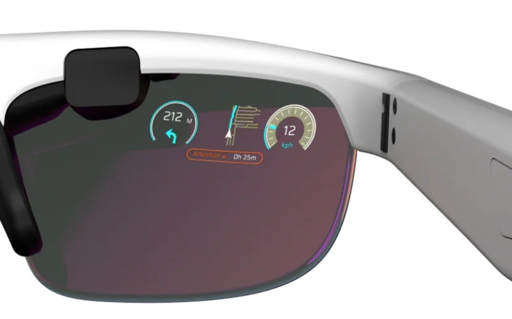 Óculos inteligentes brancos com lentes escuras exibindo informações digitais: seta para a esquerda e 212 metros, um gráfico de barras e 12 km/h, e um aviso de 0h 35m