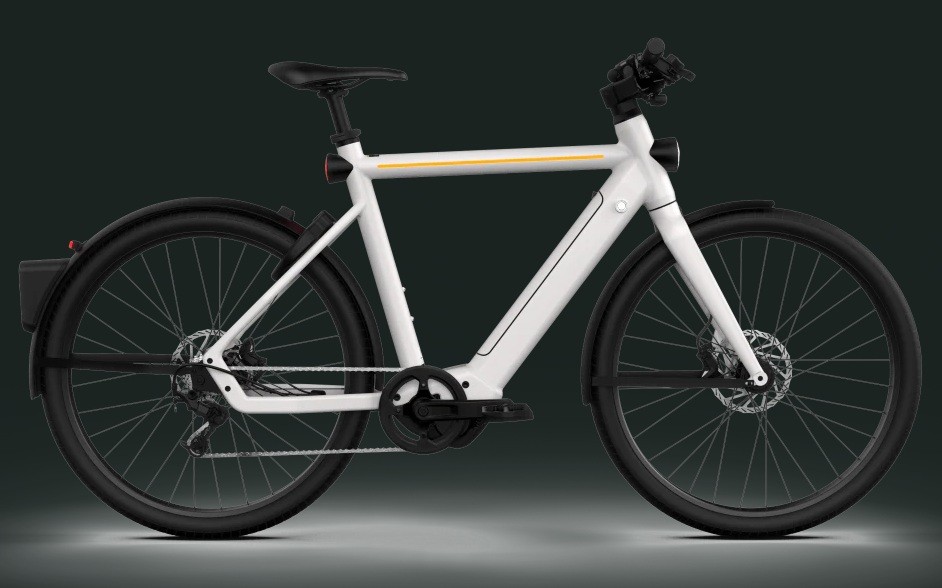 Bicicleta elétrica branca com detalhes em amarelo no quadro, guidão preto, selim preto e pneus pretos, vista lateralmente sobre fundo escuro