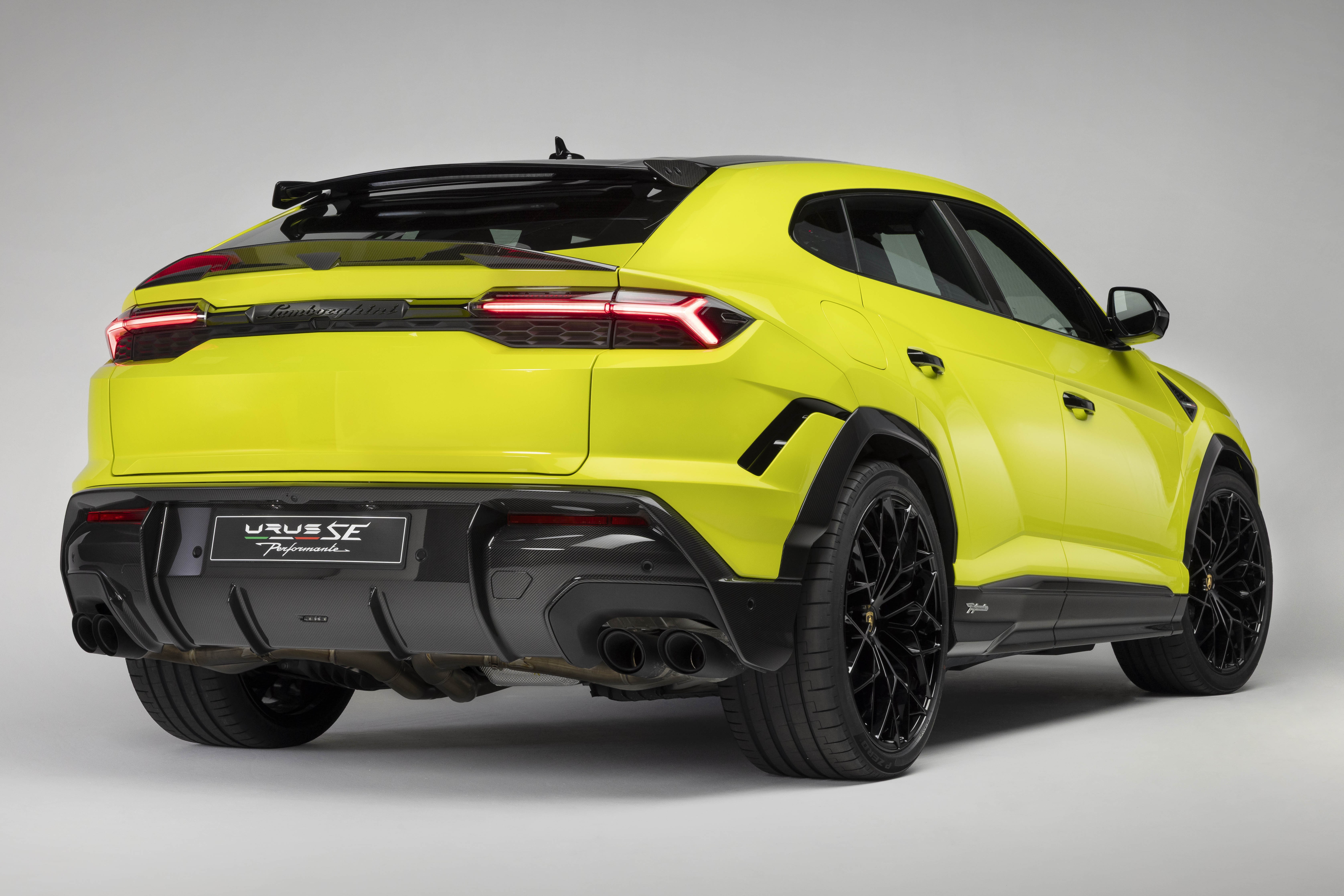 SUV Lamborghini Urus SE Performante amarelo-limão, visto de trás e lateral, com lanternas traseiras acesas, difusor e escapamento duplos pretos, rodas pretas e detalhes aerodinâmicos pretos