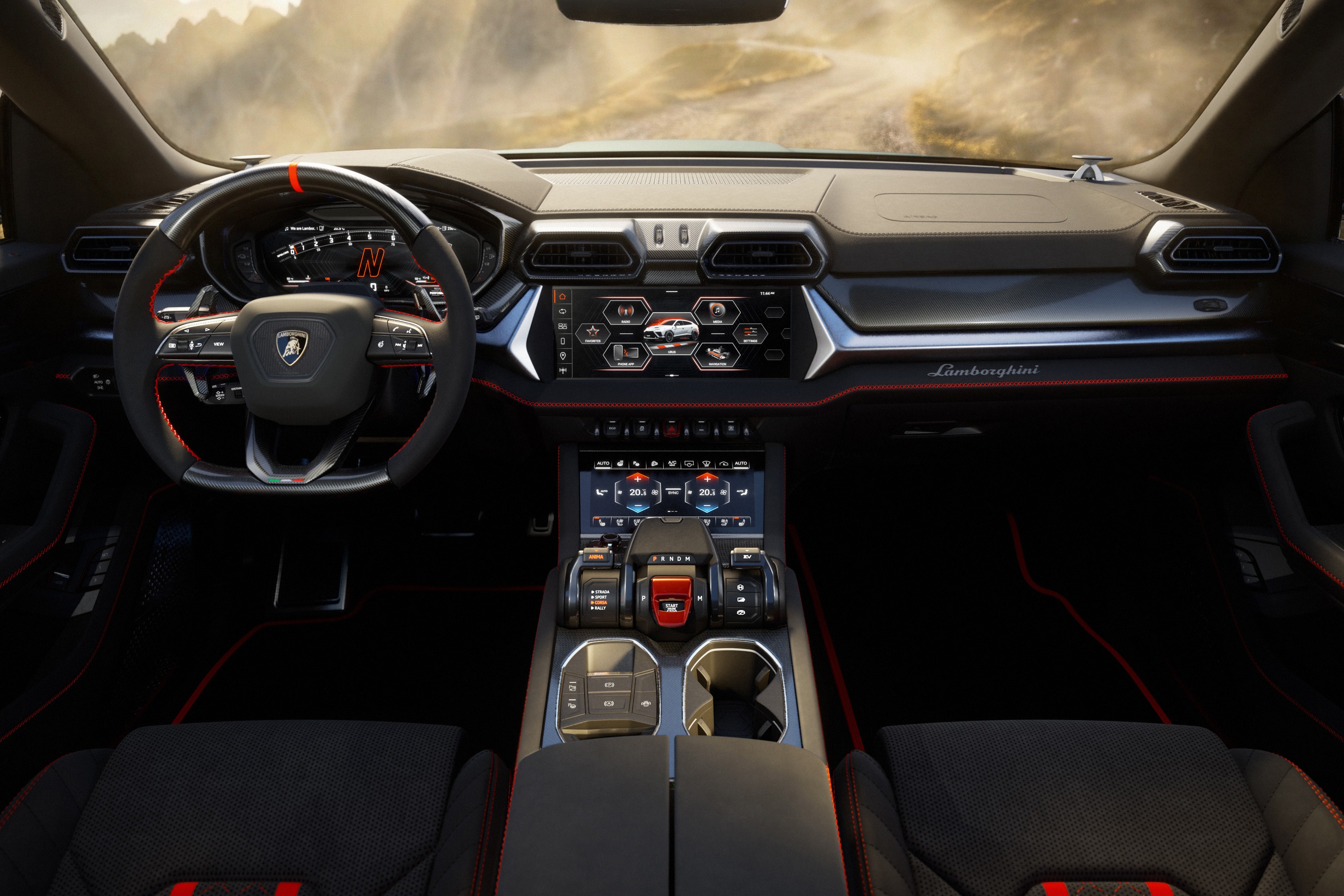 Interior de um Lamborghini Urus, com volante esportivo preto e detalhes vermelhos, painel digital, duas telas sensíveis ao toque no console central e bancos de couro preto com costuras vermelhas. Ao fundo, uma paisagem montanhosa embaçada