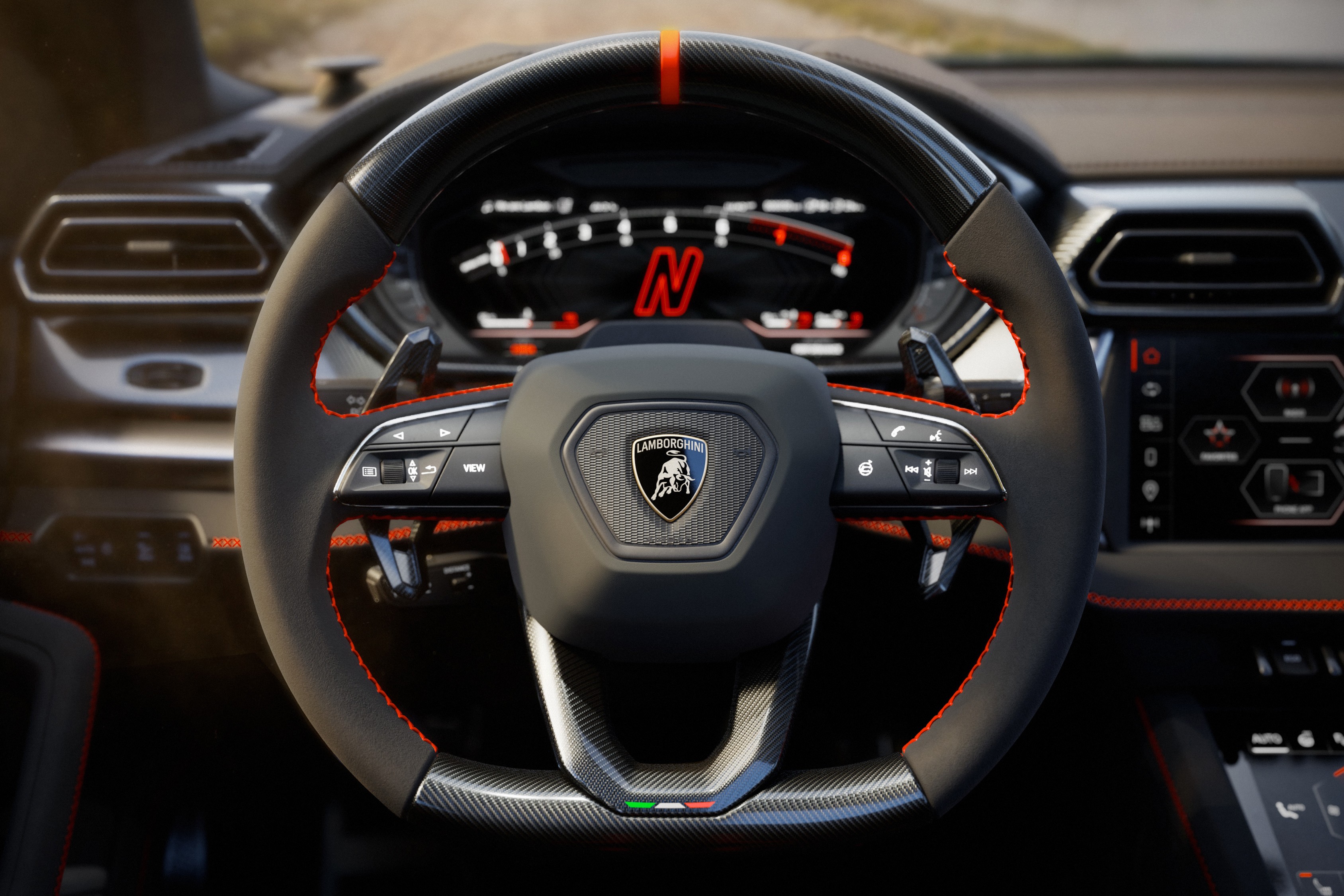 Volante de carro esportivo Lamborghini Urus em couro preto com costura vermelha, detalhes em fibra de carbono e o emblema da marca ao centro. O painel digital exibe a letra N em vermelho, indicando o modo de condução.