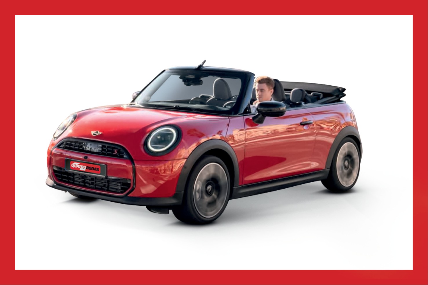 Homem de cabelo claro dirigindo um carro Mini Cooper conversível vermelho, com capota abaixada, em movimento, sobre fundo branco
