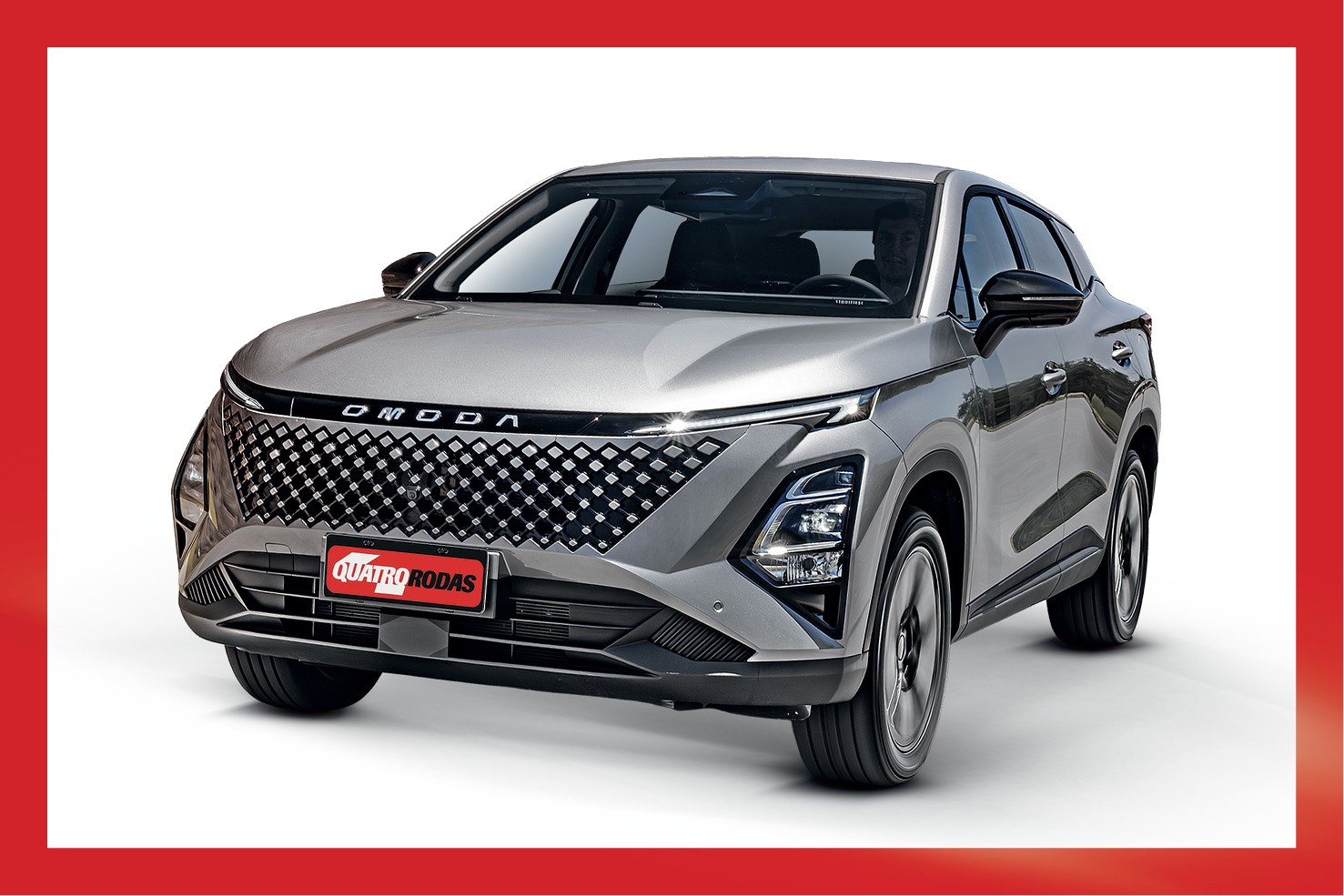 SUV Omoda 5 cinza-prateado, com grade frontal preta em formato de diamante e faróis divididos, visto de frente e ligeiramente à direita, com o logotipo Quatro Rodas na placa dianteira, em fundo branco