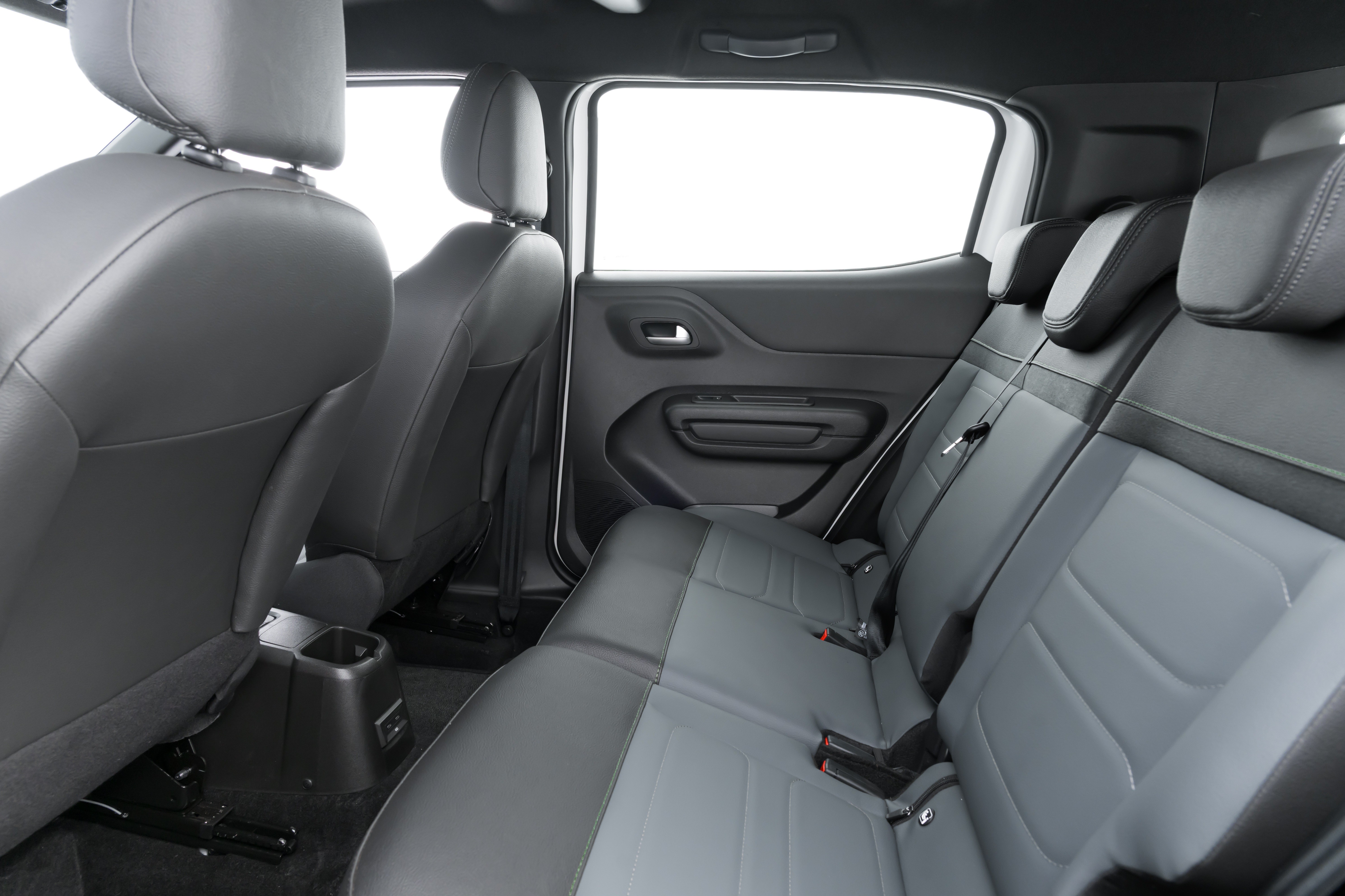 Interior de um carro com bancos traseiros em couro cinza-escuro e detalhes em cinza-claro, com encostos de cabeça e cintos de segurança visíveis. A porta traseira direita está aberta, revelando a janela e o painel interno em plástico preto. Há um console central entre os bancos dianteiros com porta-copos.