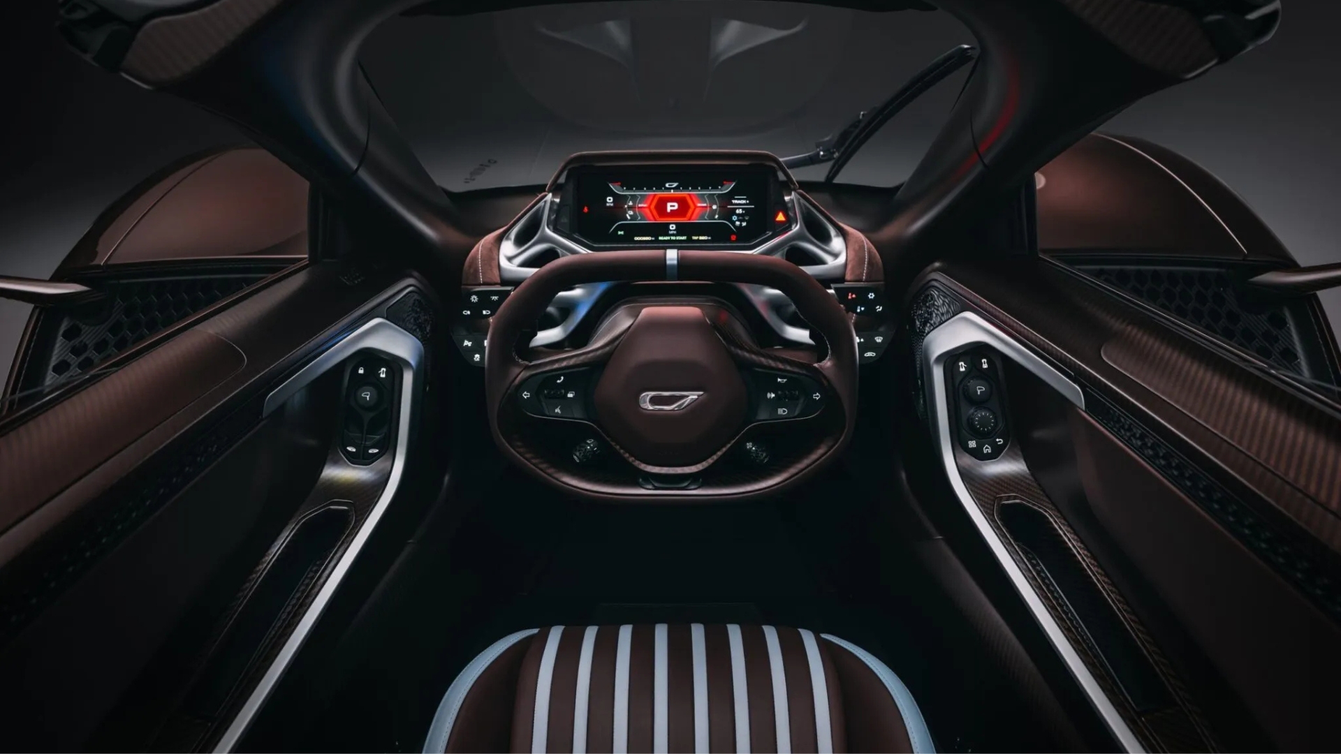 Interior de um carro esportivo de luxo, com bancos de couro marrom e listras brancas. O volante de couro marrom tem um emblema prateado e botões de controle. O painel digital exibe informações em vermelho e branco, incluindo um P de estacionamento. As portas têm detalhes em fibra de carbono e acabamento prateado, com botões de controle de janela e espelho. O para-brisa é visível ao fundo