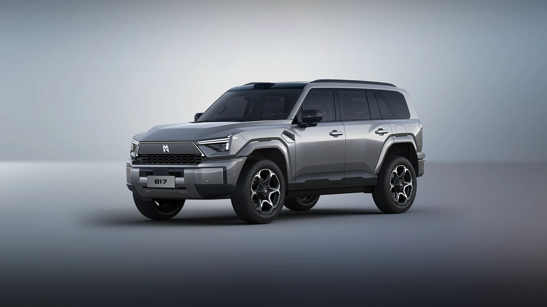 SUV cinza-prateado com teto preto, rodas pretas e detalhes prateados, parado em estúdio com fundo cinza claro. A placa frontal exibe 817